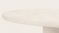 Close-up van een ronde tafel met een grof tafelblad met steenstructuur en een cilindervormig onderstel.
