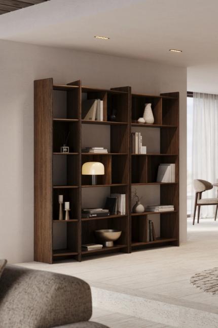 Donkerhouten open kast met boeken en decoratie in een licht interieur met eetruimte en fauteuils.