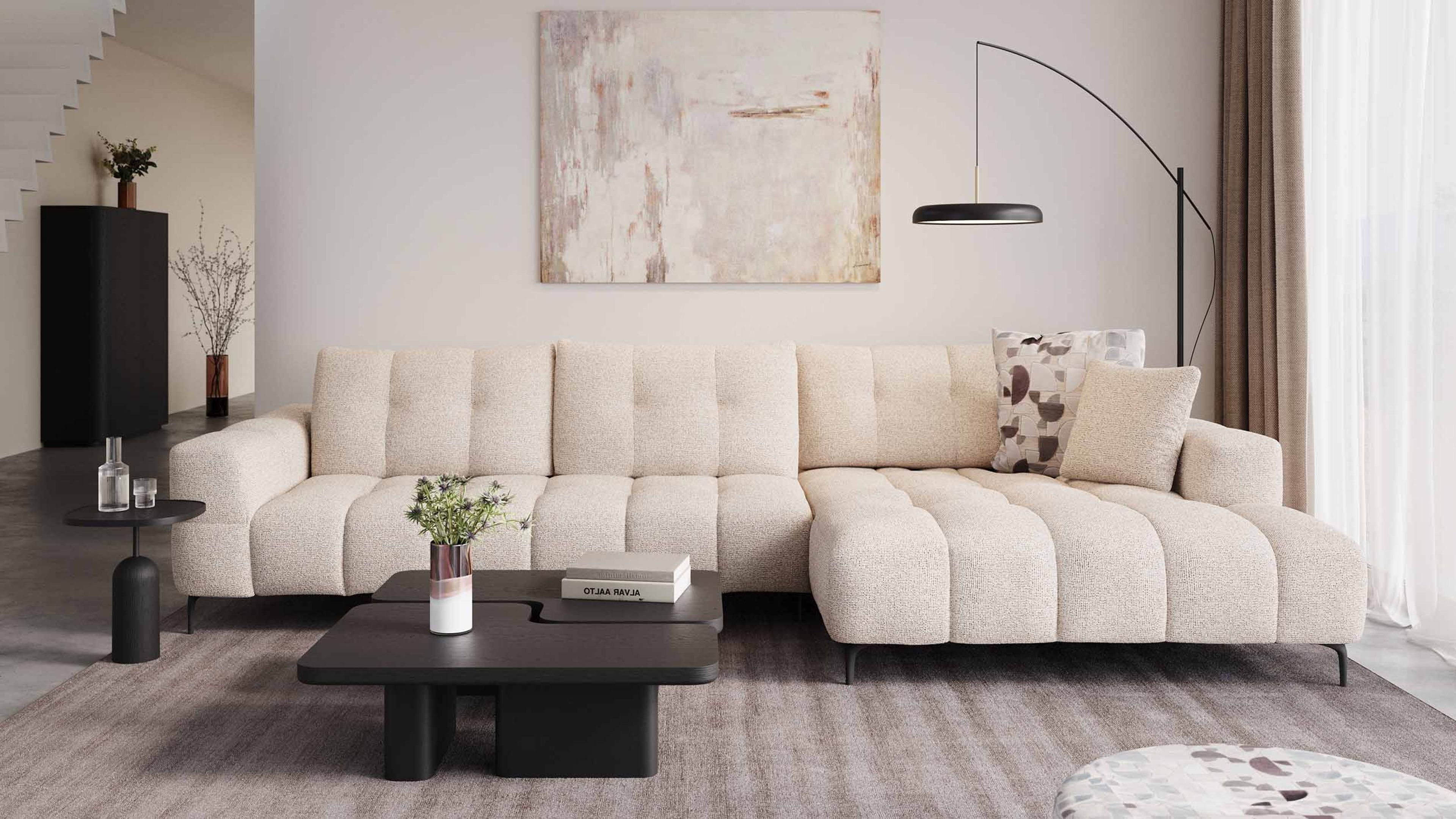 Beige hoekzetel Isola in lichte woonkamer met grote ramen, houten boekenkast, lage salontafel en zachte natuurlijke materialen.