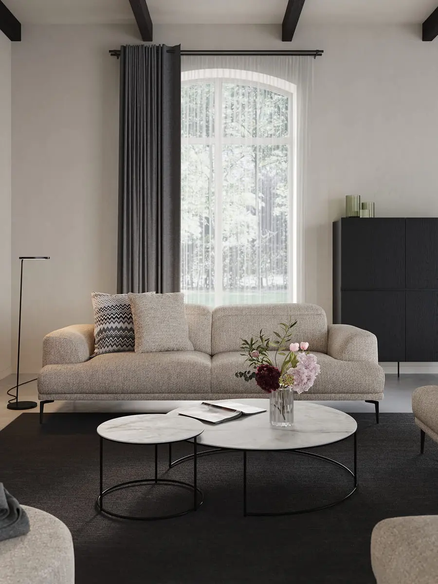 Grijze zetel Funchal in lichte woonkamer met ronde marmeren salontafels, zwarte kast, grote ramen en een vaas met bloemen.