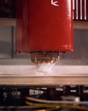 Frees bewerkt een houten plaat; zaagsel spat op onder de rode machinekop in het atelier.