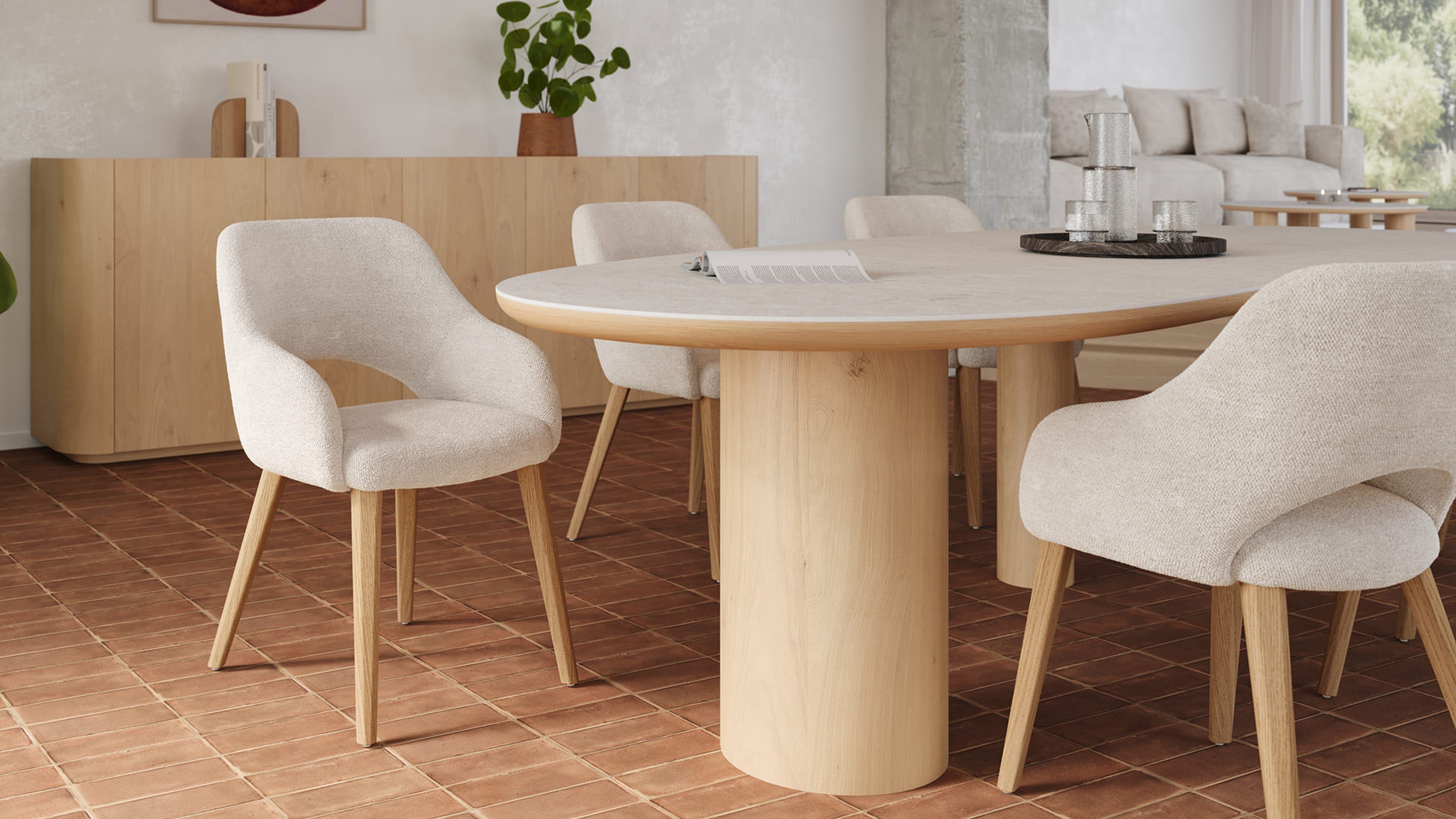 Ronde eettafel in licht hout met cilindervormige poten, omringd door beige gestoffeerde stoelen op houten poten in een warme eetruimte.