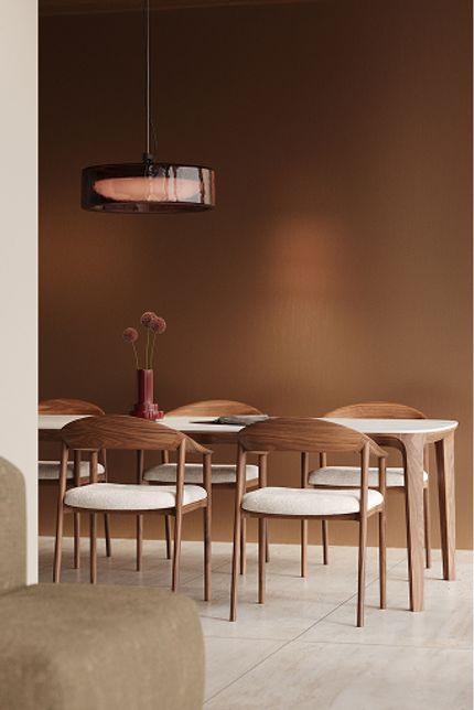 Een moderne eetkamertafel met marmeren blad, houten stoelen en een koperen hanglamp, met een vaas bloemen op de tafel.