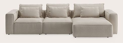 Canapé modulaire Duomo avec trois modules d’assise et coussins en tissu beige clair sur fond neutre.