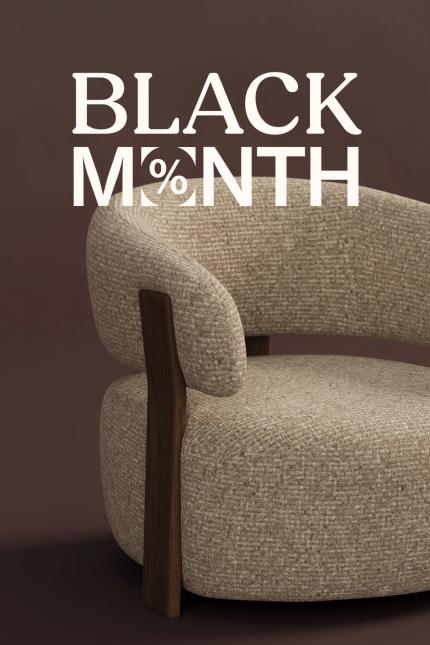 Black Month bij JUNTOO met een beige stoffen fauteuil met gebogen rugleuning, ronde zitting en donker houten frame tegen een donkerbruine achtergrond.