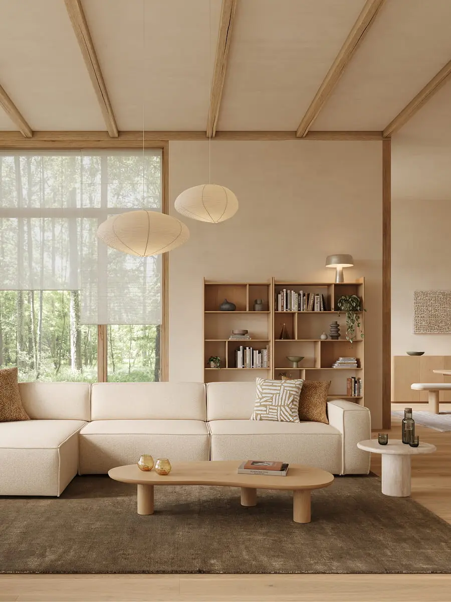 Beige hoekzetel Isola in lichte woonkamer met grote ramen, houten boekenkast, lage salontafel en zachte natuurlijke materialen.
