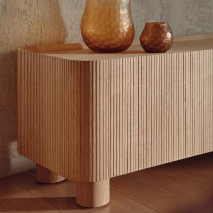 Een stijlvolle houten kast met verticaal geprofileerde lijnen, aangevuld met elegante glazen vazen. Het ontwerp benadrukt de textuur en het vakmanschap van het materiaal.