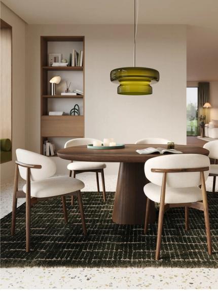 Piola stoel met houten frame en licht gestoffeerde zitting rond een ronde houten eettafel in een warm, modern interieur.