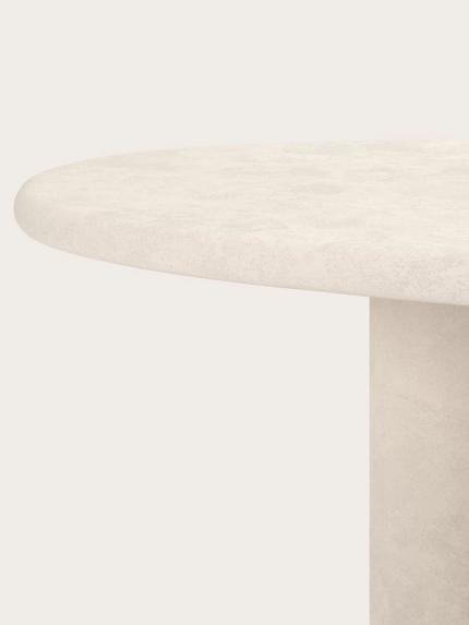 Close-up van een ronde tafel met een grof tafelblad met steenstructuur en een cilindervormig onderstel.