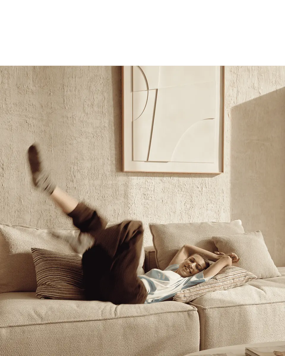 Vrouw speelt uitgelaten op een comfortabele zetel in een warm huiselijk interieur