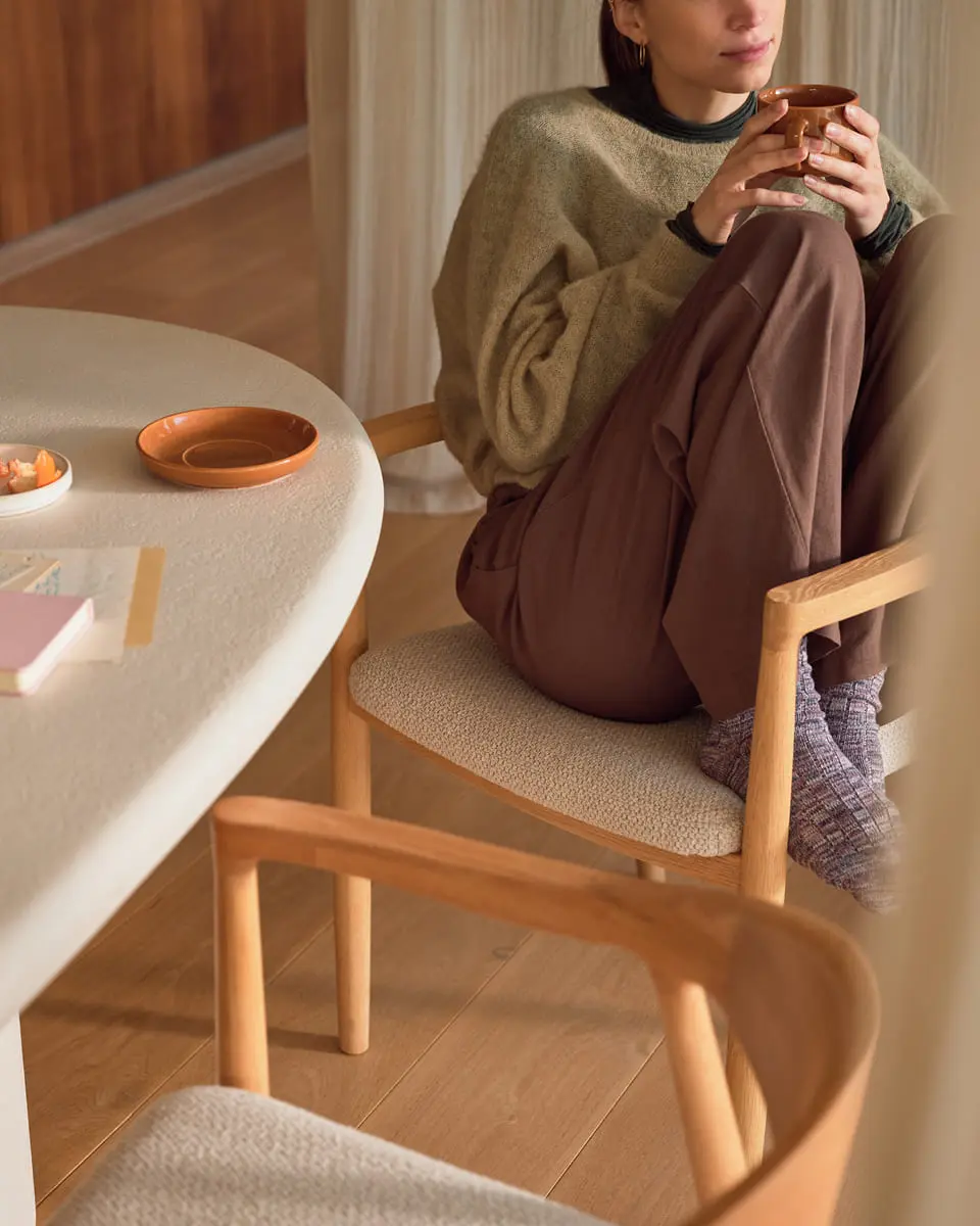 Minimalistisch interieur met grijs bankstel, houten salontafel en grote planten in een lichte woonkamer
