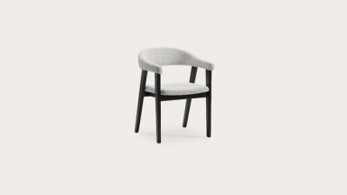 Gubbio stoel met lichtgrijze stoffering en afgeronde arm- en rugleuning op zwart houten frame.