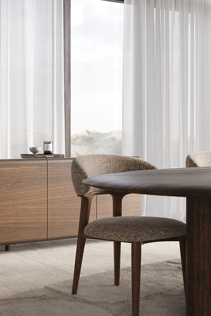 Divino dressoir in hout naast een donkere eettafel met gestoffeerde stoelen in een lichte eetruimte.