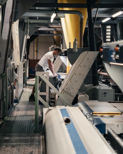 Collaborateur au travail parmi des machines industrielles dans un atelier de production textile.