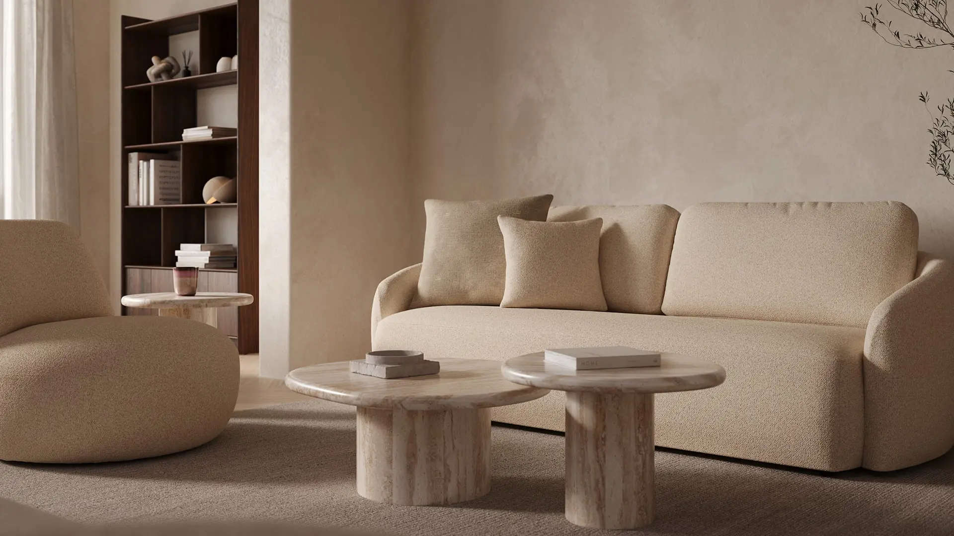 Fauteuil Gatto en tissu bouclé clair dans un salon chaleureux, à côté d’un canapé beige et de deux tables basses rondes en marbre sur un grand tapis.