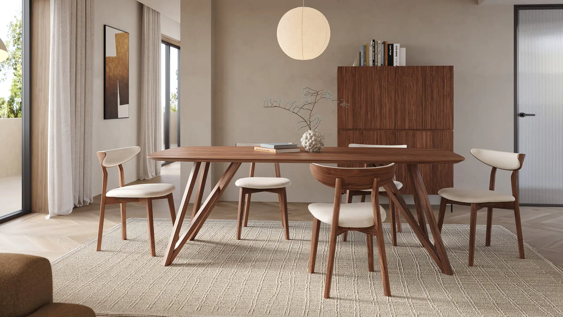 Tapis Nanda beige sous une table à manger en bois avec chaises design, dans une salle à manger lumineuse aux tons neutres avec suspension et buffet.