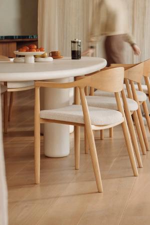Moderne eettafel met houten stoelen, een ronde tafel en een zacht gekleurde achtergrond, met een persoon in beweging