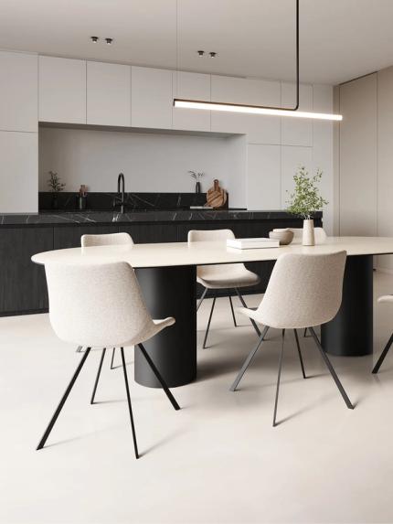 Een moderne eetkamer met een elegante ronde tafel en comfortabele stoelen. De open keuken op de achtergrond heeft een zwart-marmeren werkblad en minimalistische witte kastdeuren, verlicht door een strakke hanglamp.