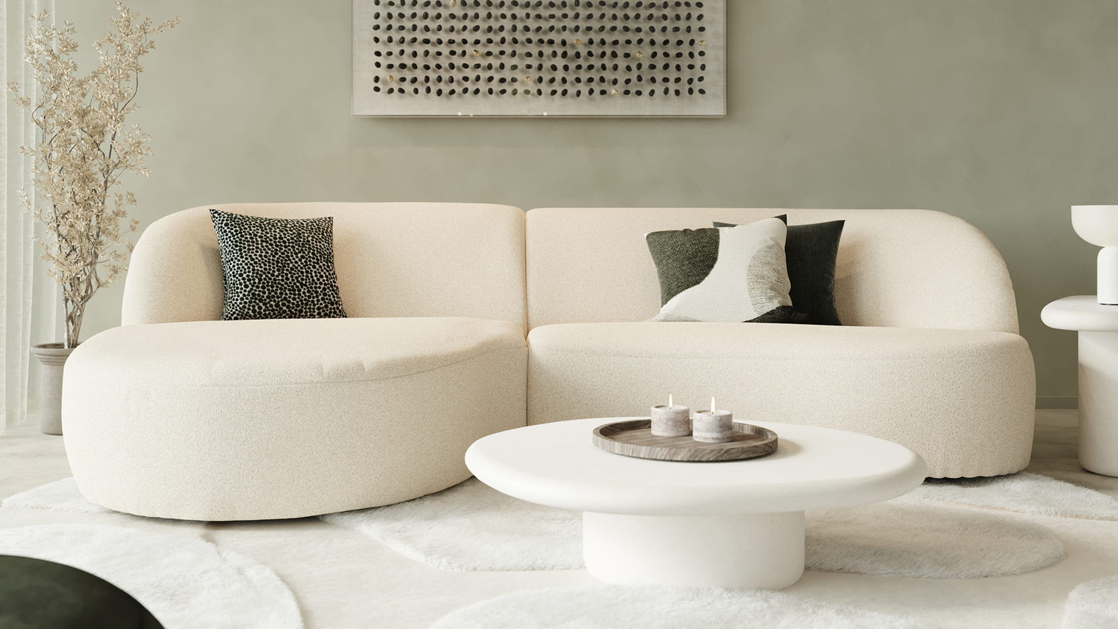 Canapé Tubo beige aux formes arrondies dans un salon apaisant avec table basse ronde, tapis doux et mur vert.