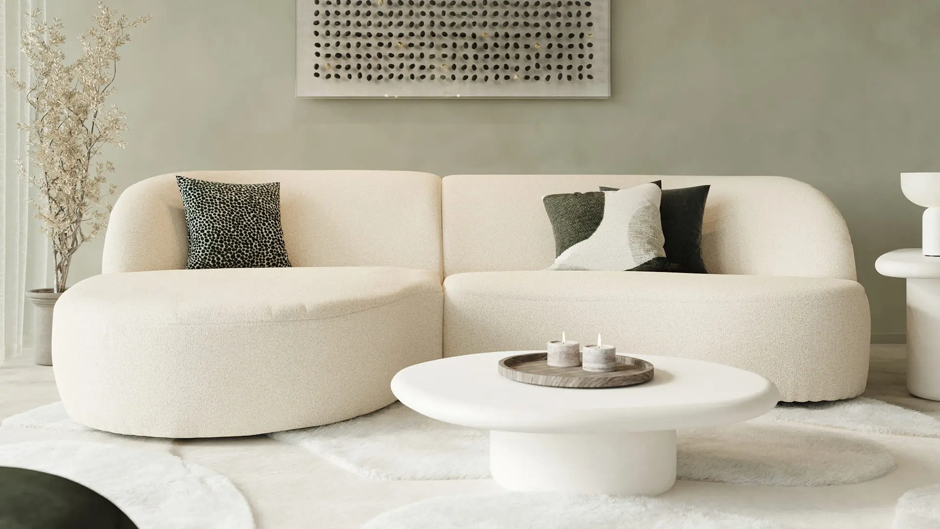 Beige zetel Tubo met afgeronde vormen in rustige woonkamer met ronde salontafel, zachte tapijten en groene wand.