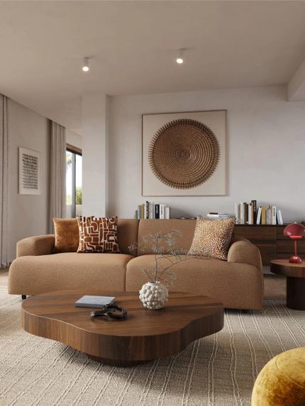 Bruine zetel Coimbra met sierkussens in warme woonkamer met houten salontafel, fauteuil, groot wandkunstwerk en lichte gordijnen.