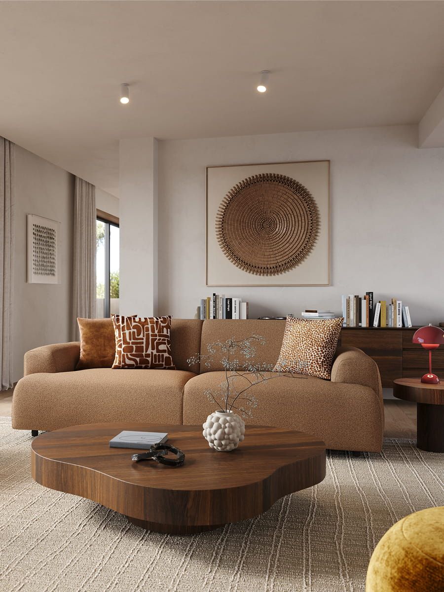 Bruine zetel Coimbra met sierkussens in warme woonkamer met houten salontafel, fauteuil, groot wandkunstwerk en lichte gordijnen.