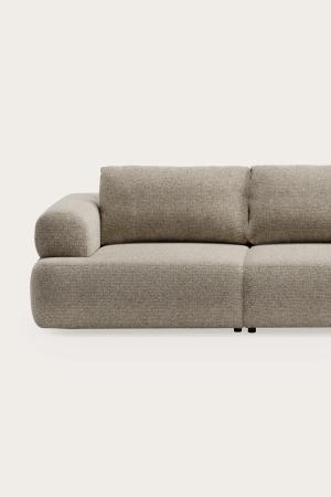 Beige gestoffeerde zetel met brede armleuning, losse rugkussens en afgeronde volumes tegen een neutrale achtergrond.