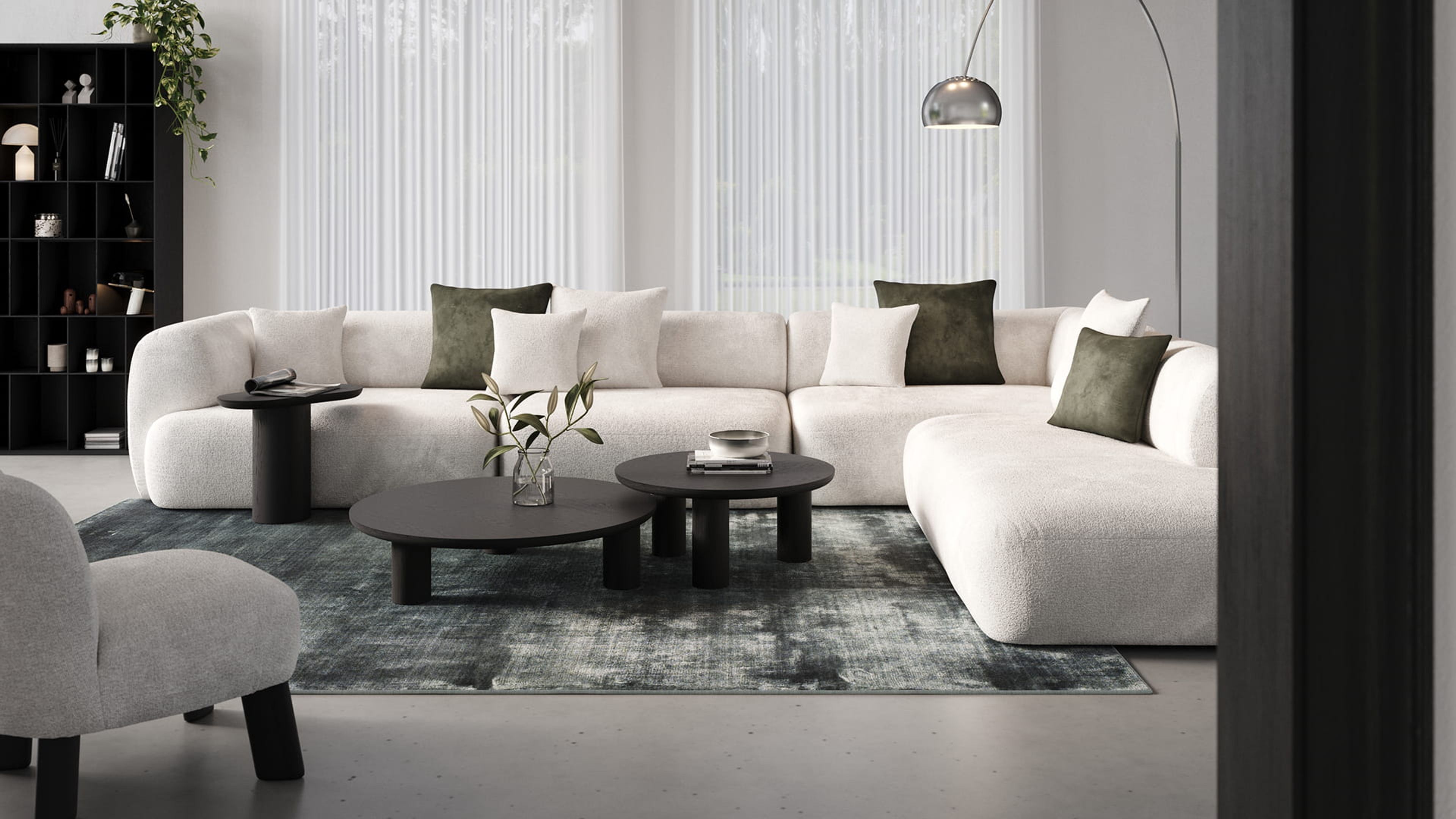 Table basse Amato ronde noire sur un tapis devant un canapé modulable beige dans un intérieur moderne.