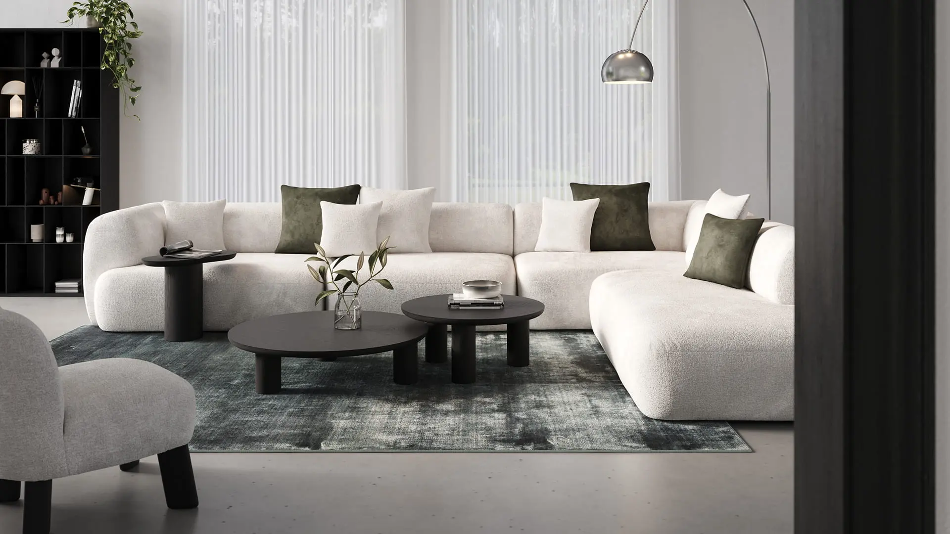 Table basse Amato ronde noire sur un tapis devant un canapé modulable beige dans un intérieur moderne.