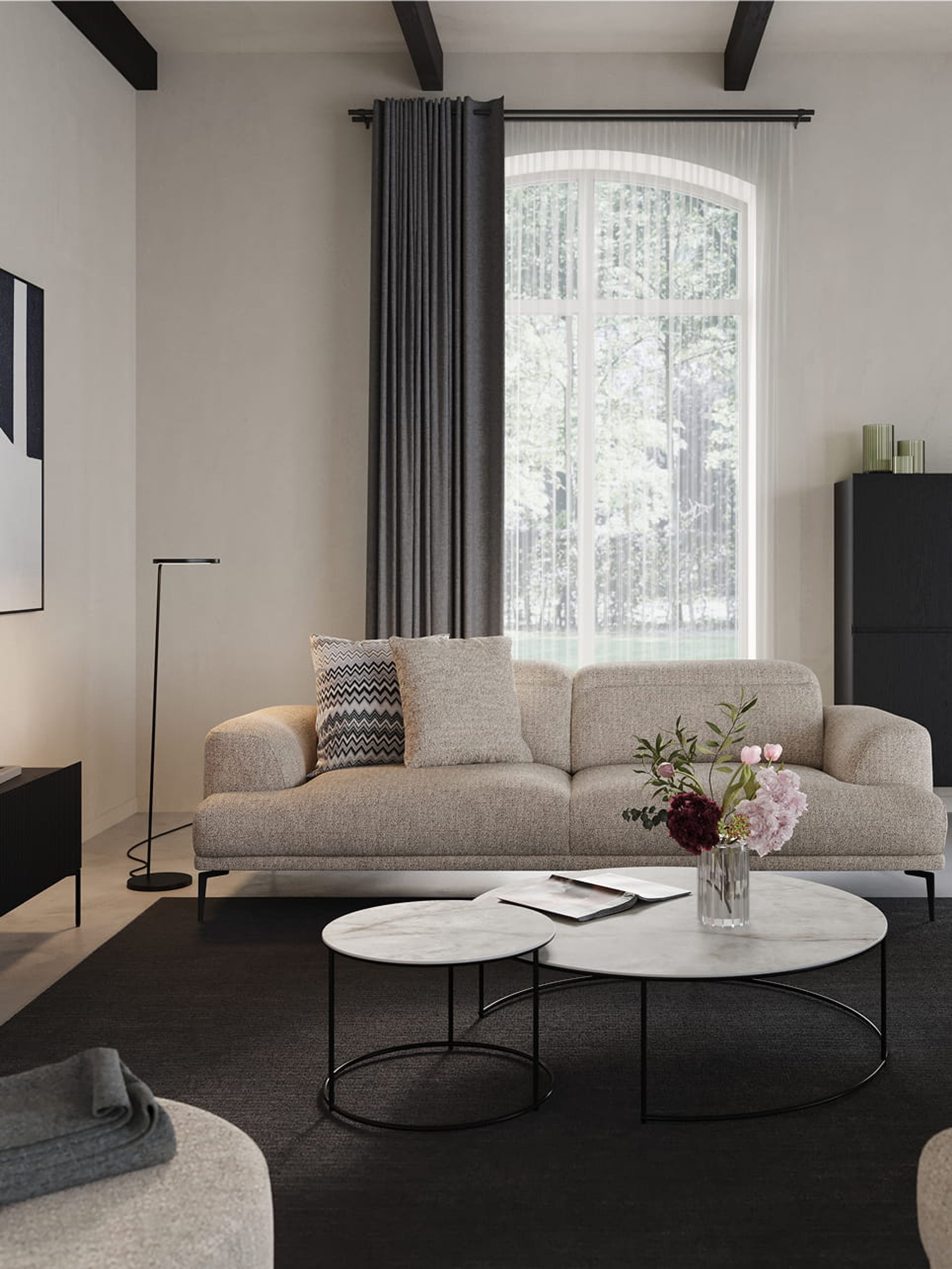 Tables basses Juno noires sur un tapis devant un canapé modulable beige dans un intérieur moderne.