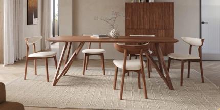 Compacte eetruimte met slanke houten tafel en vier stoelen op een licht vloerkleed, met houten kast en zachte daglichtinval.