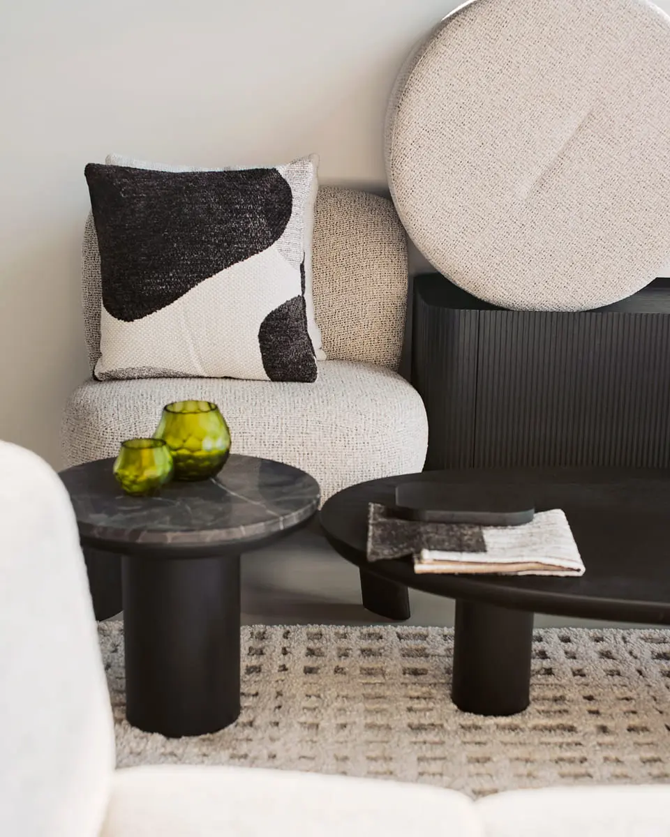 Coin salon moderne avec une table basse en marbre, des photophores en verre et un coussin rembourré.