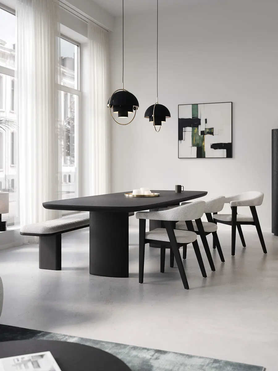 Salle à manger minimaliste avec longue table noire, chaises claires et banc, suspensions noires et hautes fenêtres avec voilages.