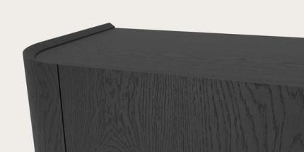 Detail van Rondato kast in zwart hout, met afgeronde hoek en zichtbaar houtnerfpatroon op het bovenblad en front.