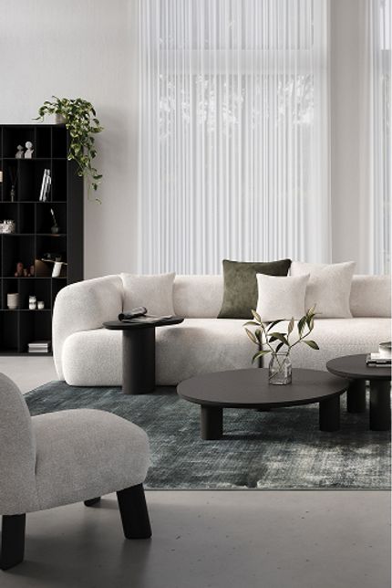 Moderne woonkamer met lichte hoekzetel, drie zwarte bijzettafels en een blauwgroen tapijt voor een rustige, elegante look.