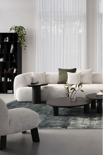 Moderne woonkamer met lichte hoekzetel, drie zwarte bijzettafels en een blauwgroen tapijt voor een rustige, elegante look.