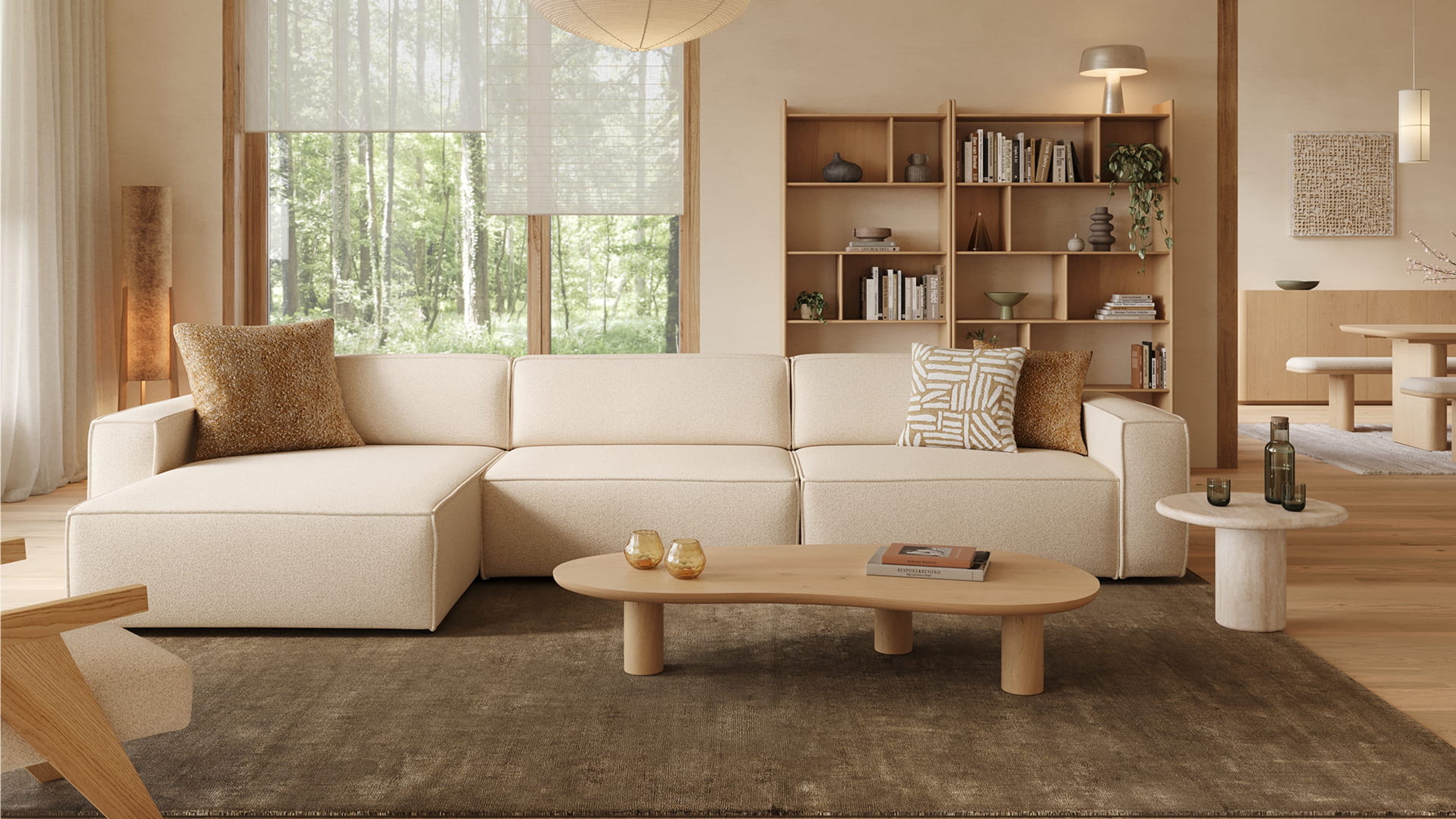 Artisano blob salontafel met organische vorm en lichte afwerking, voor een beige hoekzetel op een donker tapijt.