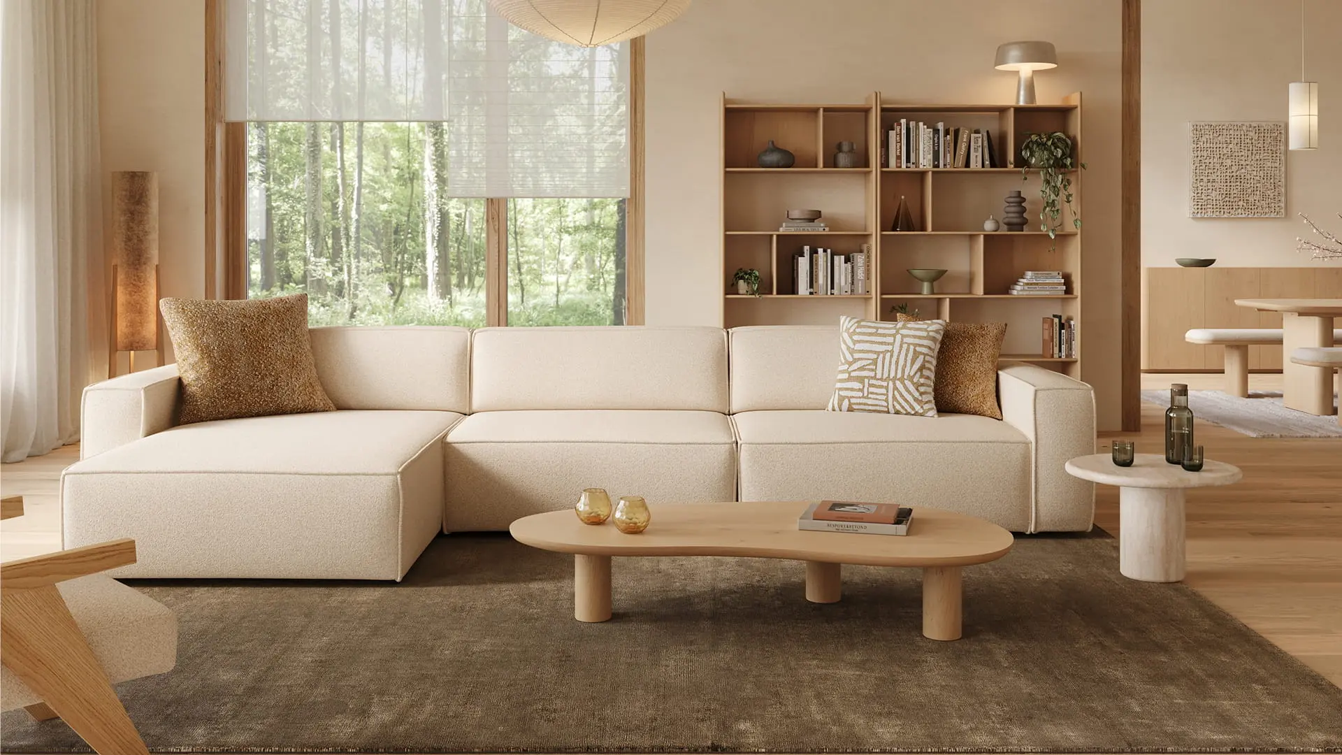 Table basse Artisano forme organique blob, finition claire, devant un canapé d’angle beige sur un tapis foncé.