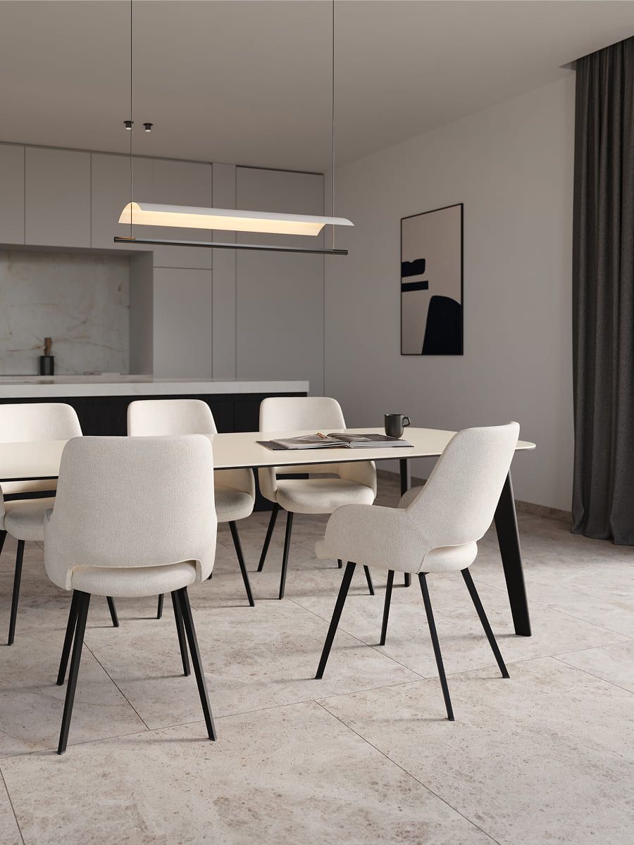 Minimalistische eetruimte met ovale eettafel, zes licht gestoffeerde stoelen en hanglamp, open keuken op de achtergrond.